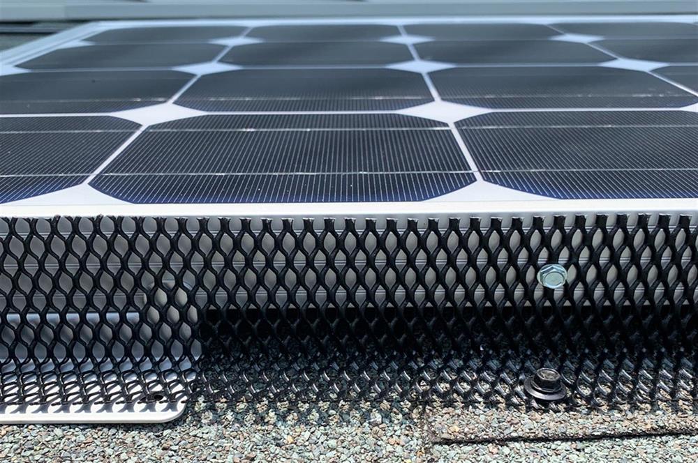 PestArmor_Tight_Messh_Excluder Black mesh critter guard installed along the edge of a rooftop solar panel.